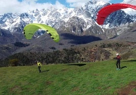 Foto de dos parapentistas con Picos de Europa de fondo.