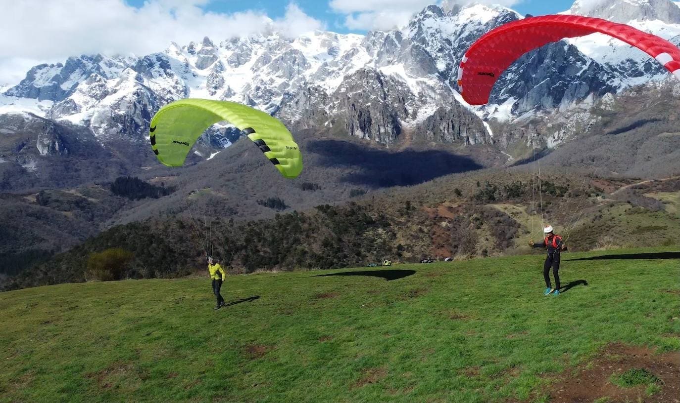 Foto de dos parapentistas con Picos de Europa de fondo.