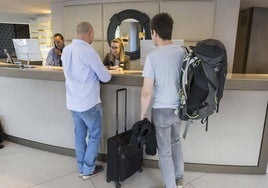 Turistas en el registro de un hotel de Santander son atendidos por una recepcionista.