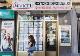 Una mujer pasa por delante de una inmobiliaria.