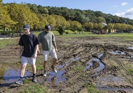 Dos turistas caminan, ayer, por el barrizal formado en la Campa de La Magdalena como consecuencia del campeonato de hamburguesas que acogió hace tres semanas.