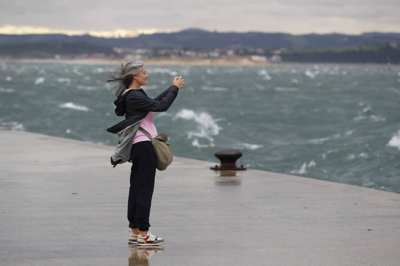 Una mujer se acerca al paseo para fotografiar la bahía