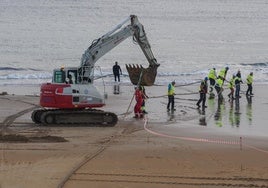 Los operarios llevan a cabo el desembarco del cable submarino de Meta en la playa de la Virgen del Mar (Santander).