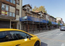 Un vehículo atraviesa la avenida principal del barrio donde se han apuntalado los edificios.