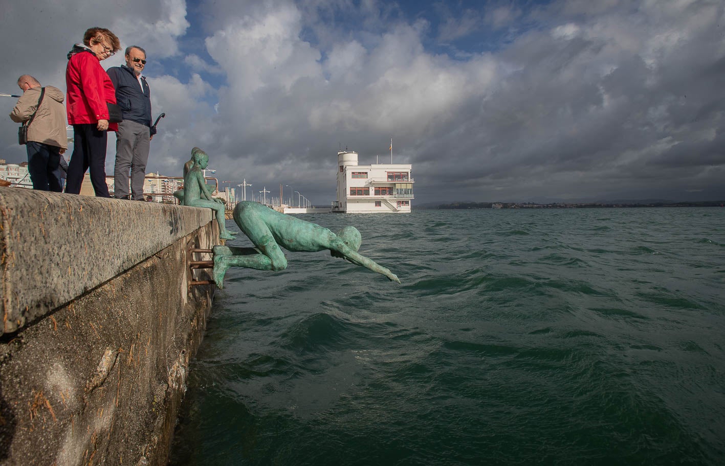 Dos ciudadanos observan el mar junto al monumento a Los Raqueros en Santander