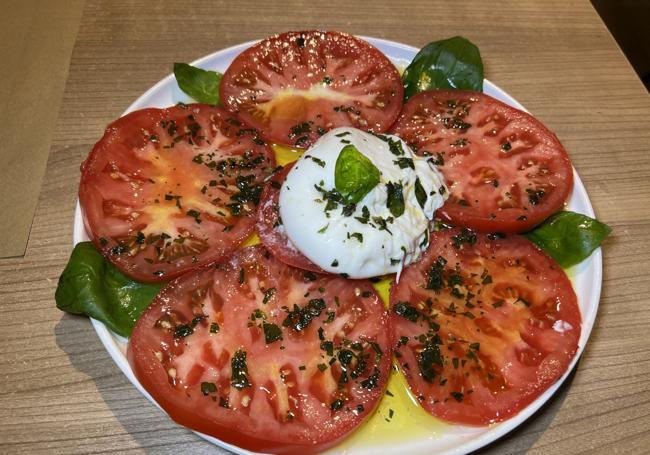 Ensalada de tomate de Cantabria, burrata y albahaca. Abajo, croquetas de jamón.