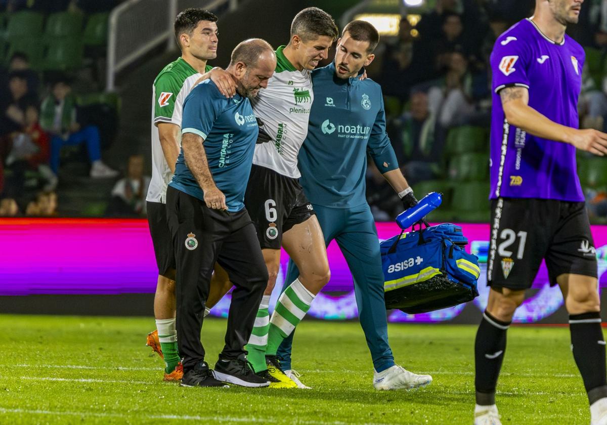 Gesto de dolor de Íñigo Sainz-Maza, abandonando el campo ayudado por dos sanitarios después de lesionarse.