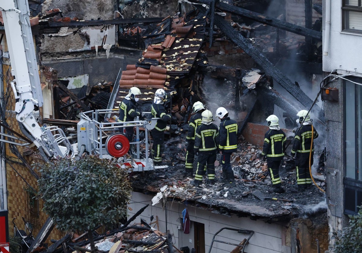 Los bomberos de Santander retiran escombro del edificio calcinado.