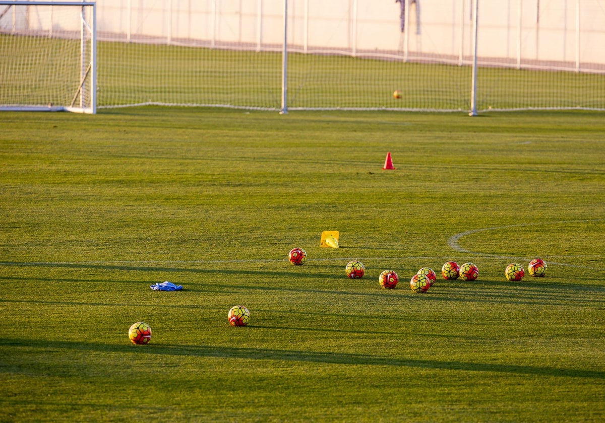 Unos balones de fútbol ocupan el centro de un campo de entrenamiento.