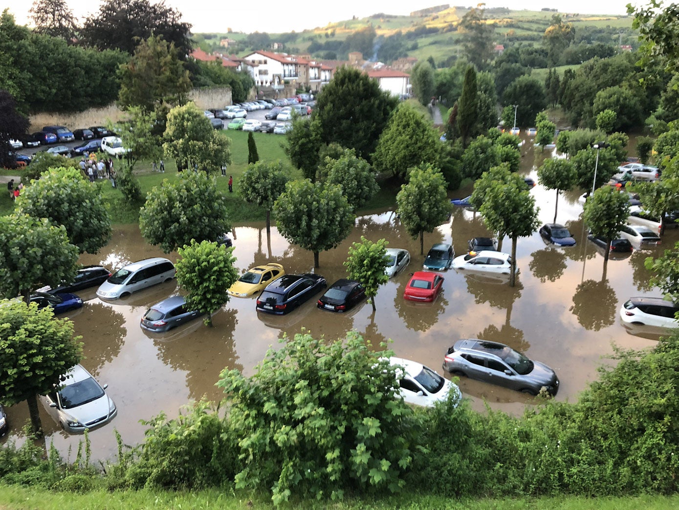 El nivel del agua llegó a superar el metro y medio de altura en las zonas más bajas del aparcamiento de Rolaceña, en Santillana del Mar, tras una fuerte tromba de agua.