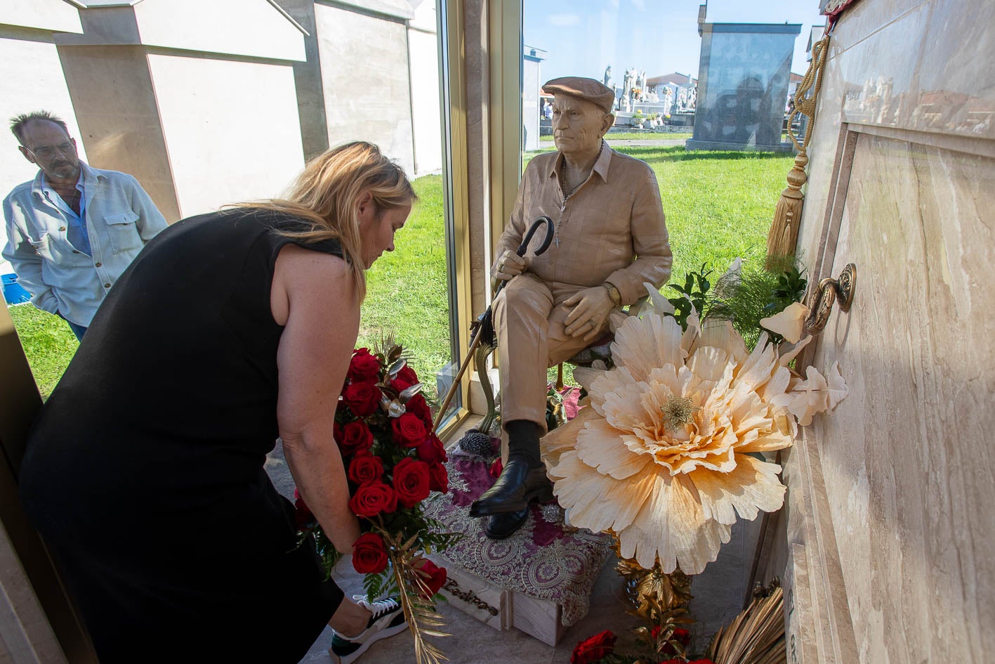 Carmen López, hija del fallecido, coloca unas flores junto a su figura.