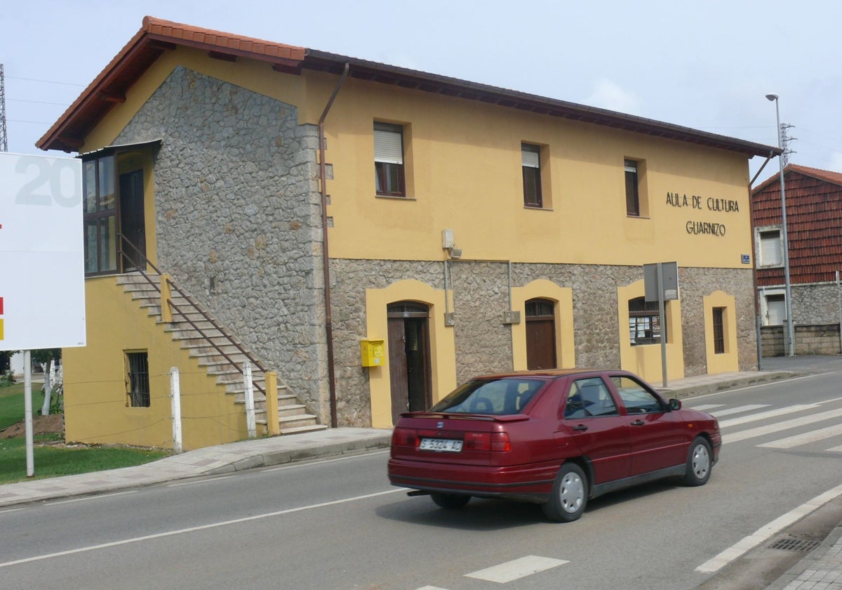 Un vehículo circula junto al Aula Cultural de Guarnizo.