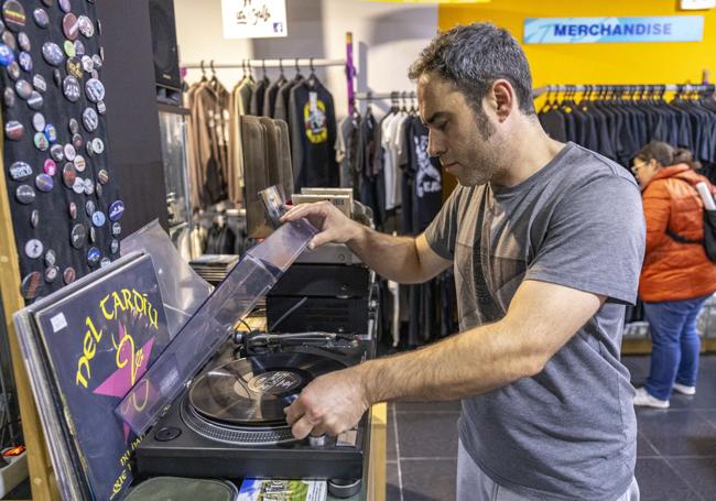 Un hombre mete un vinilo en un tocadiscos, en Tiendas Tipo.