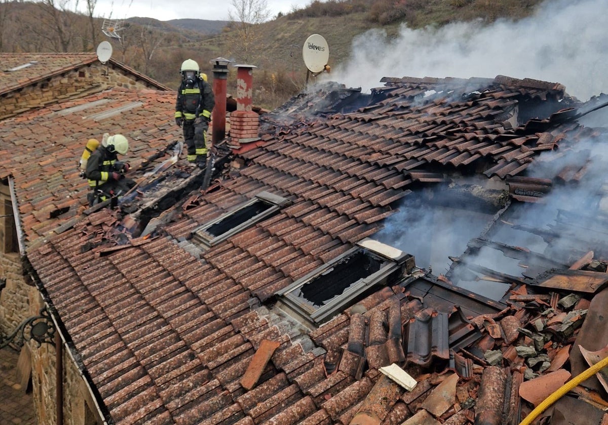 Bomberos del Gobierno regional sobre el tejado de la vivienda calcinada por el fuego.