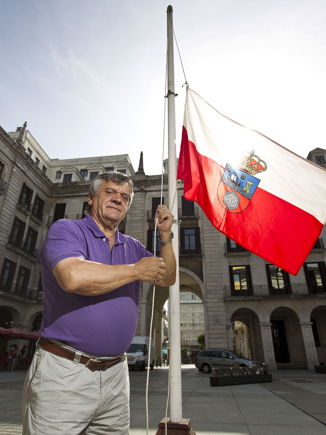 Chema Puente izando una bandera de Cantabria en la plaza Porticada de Santander durante las fiestas de Santiago.