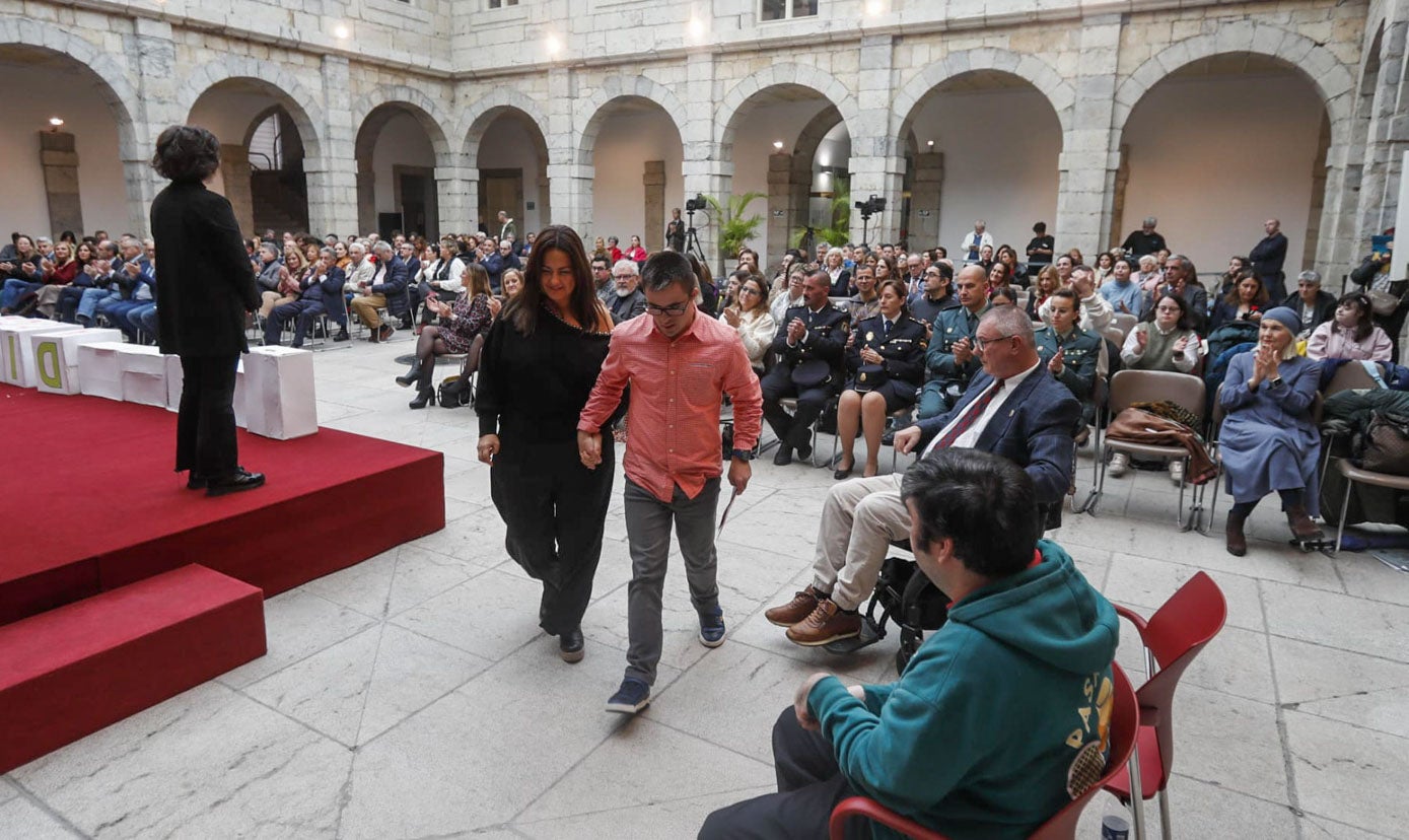 La consejera de Inclusión Social, Juventud, Familias e Igualdad Begoña Gómez del Río, acompaña al escenario a uno de los participantes.