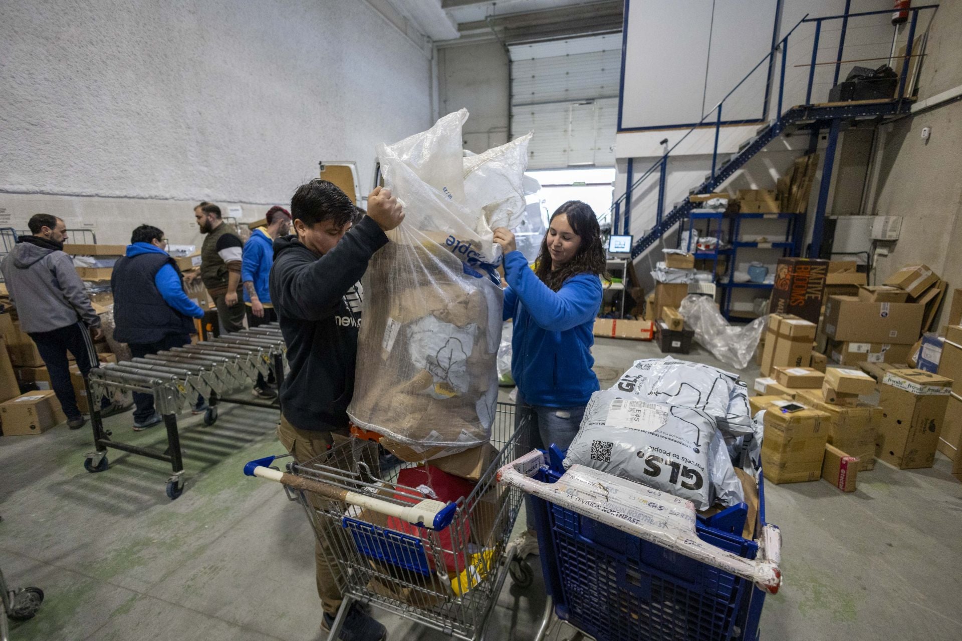 Dos trabajadores descargan en un carro cajas de cartones para reciclar.