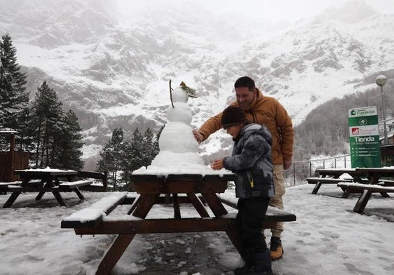 Un niño y su padre hacen un muñeco de nieve en Fuente Dé.