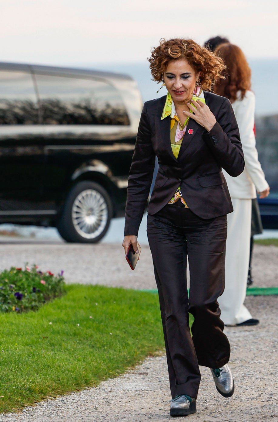 La vicepresidenta María Jesús Montero, con un traje azul, blusa estampada y zapatos plateados con plataforma. 