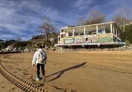 Un hombre pasea, ayer, por la playa de Los Peligros, junto al edificio abandonado de La Horadada, con grafitis y suciedad.