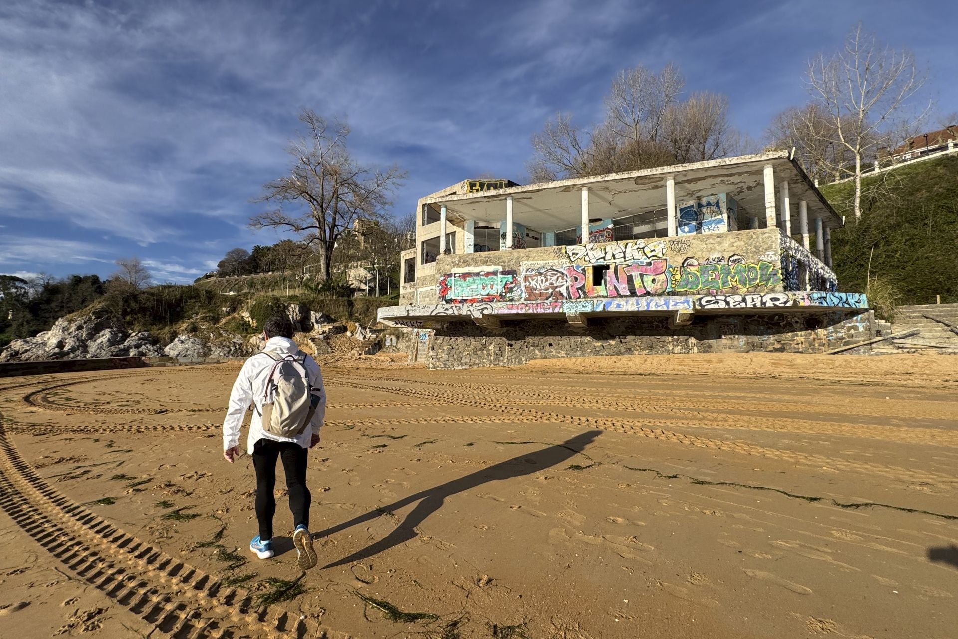 Un hombre pasea, ayer, por la playa de Los Peligros, junto al edificio abandonado de La Horadada, con grafitis y suciedad.