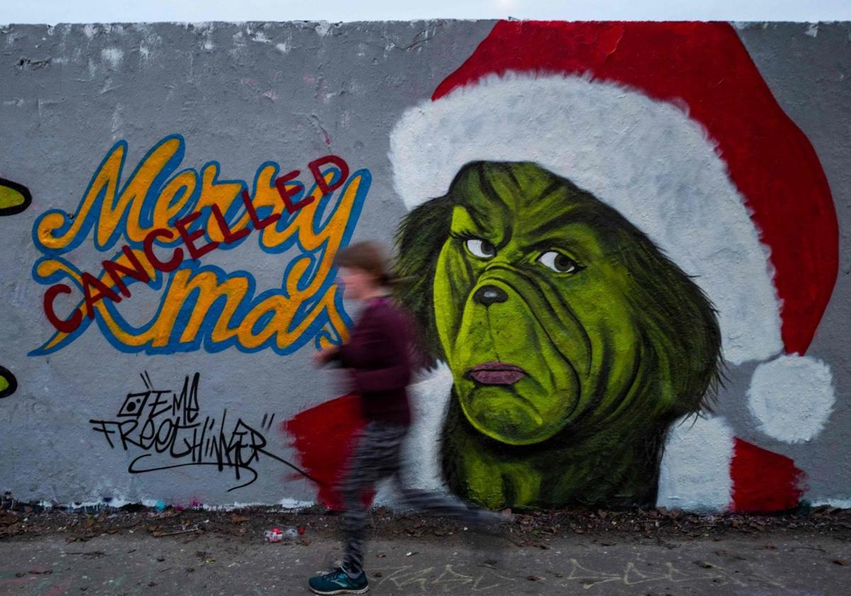 Una persona pasa ante una imagen del Grinch en un mural pintado en una fachada de Berlín.