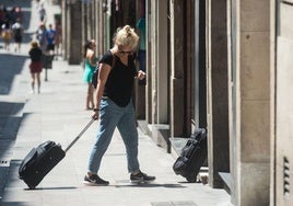 Una turista con su maleta antes de acceder a un piso turístico.