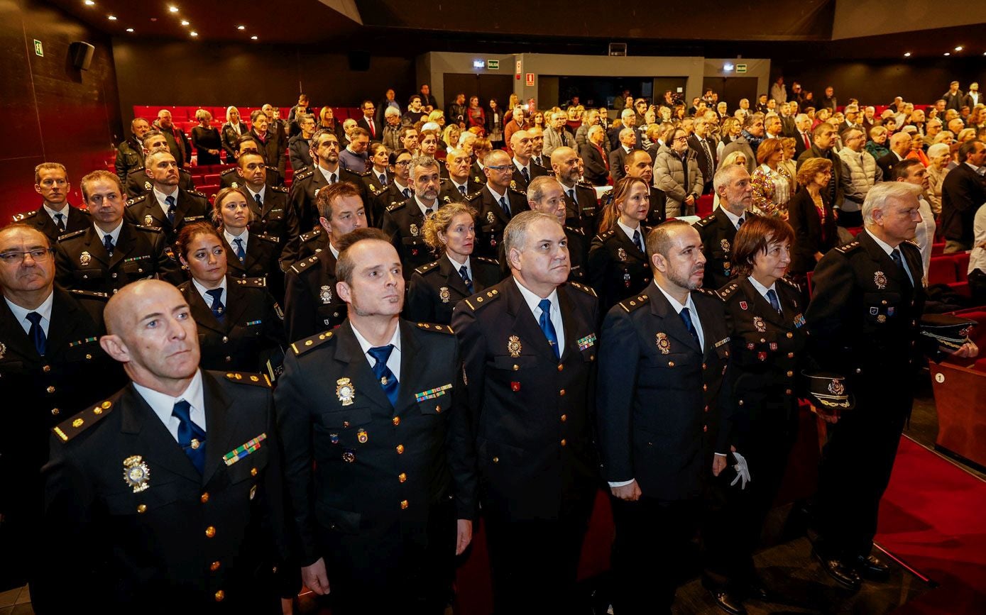 Agentes de la Policía Nacional escuchan el himno nacional junto al resto del público, este viernes, en Torrelavega.