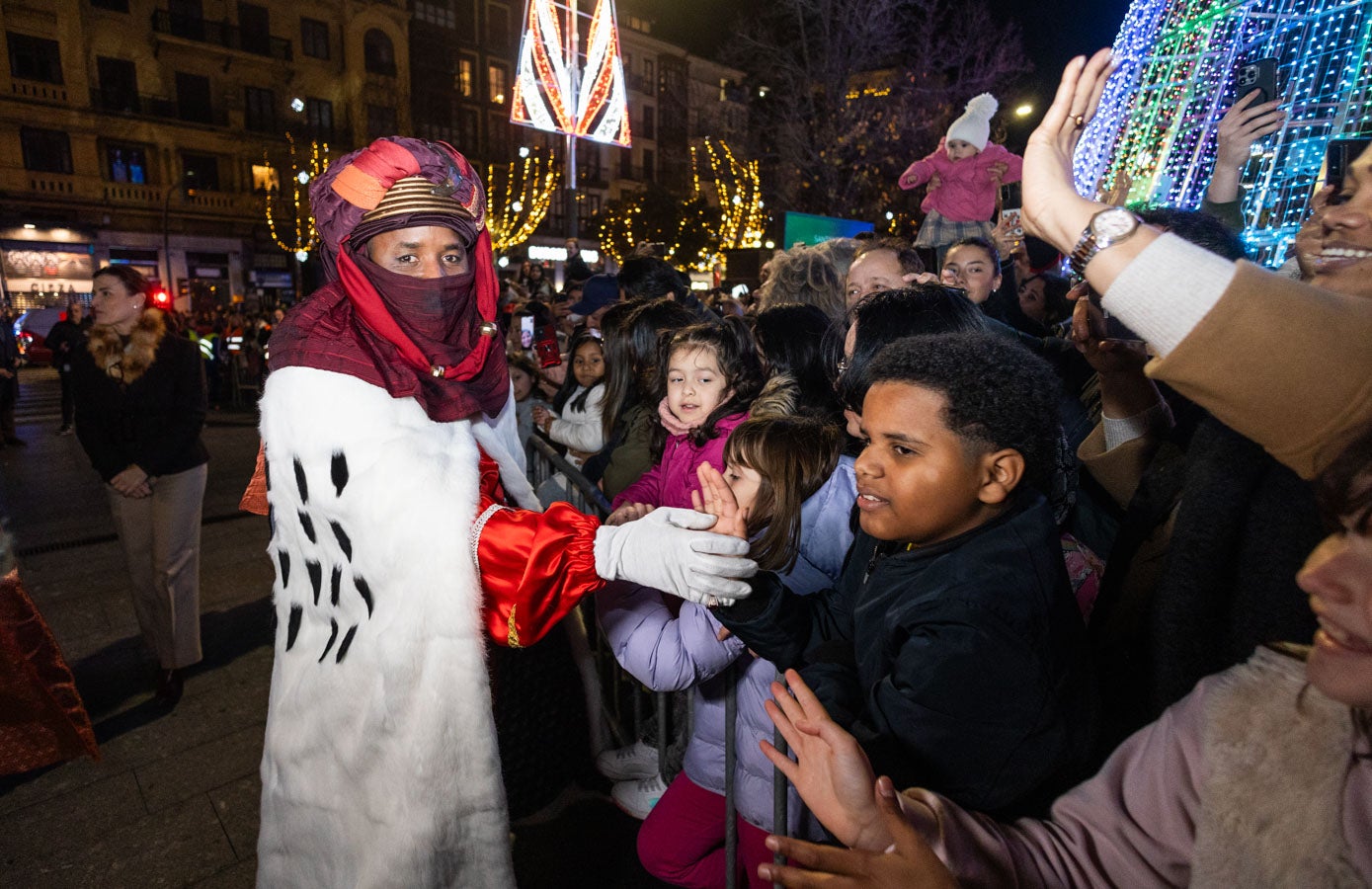 Baltasar choca la mano a un niño en la plaza del Ayuntamiento tras bajarse de su carroza.