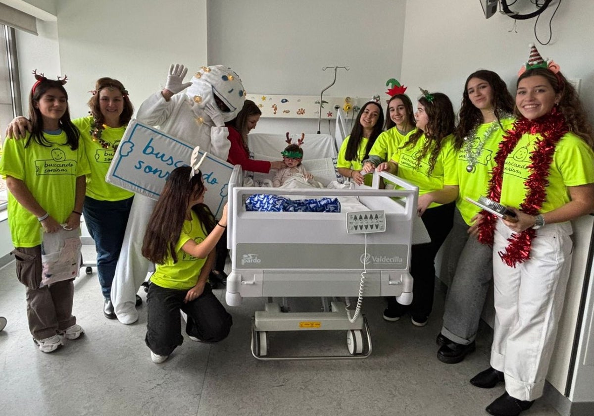 Los voluntarios, junto a la mascota de la asociación, entregan un regalo a una de las niñas ingresada en Valdecilla.