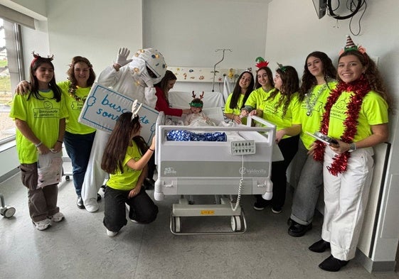 Los voluntarios, junto a la mascota de la asociación, entregan un regalo a una de las niñas ingresada en Valdecilla.