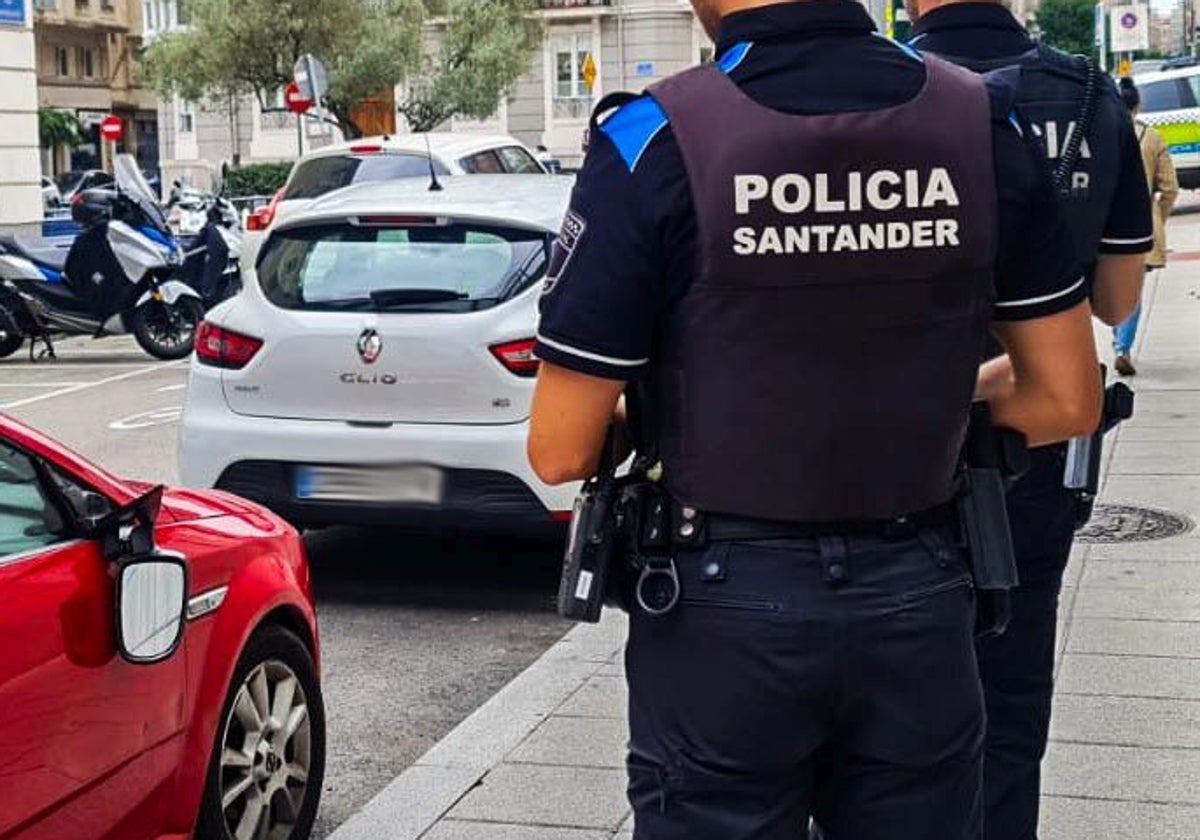 Imagen de archivo de policías de Santander observando varios vehículos estacionados con destrozos.