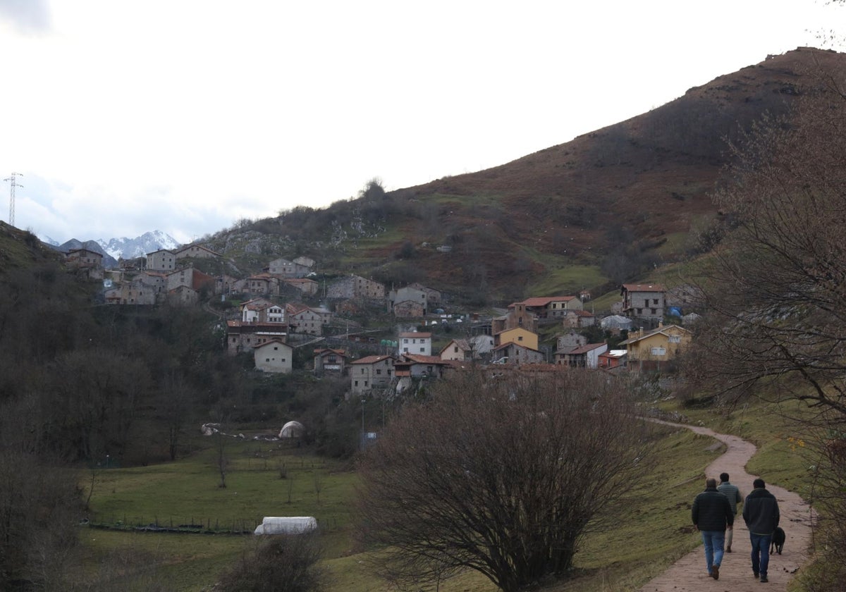 Tres personas caminan hacia el pueblo de Tresviso.