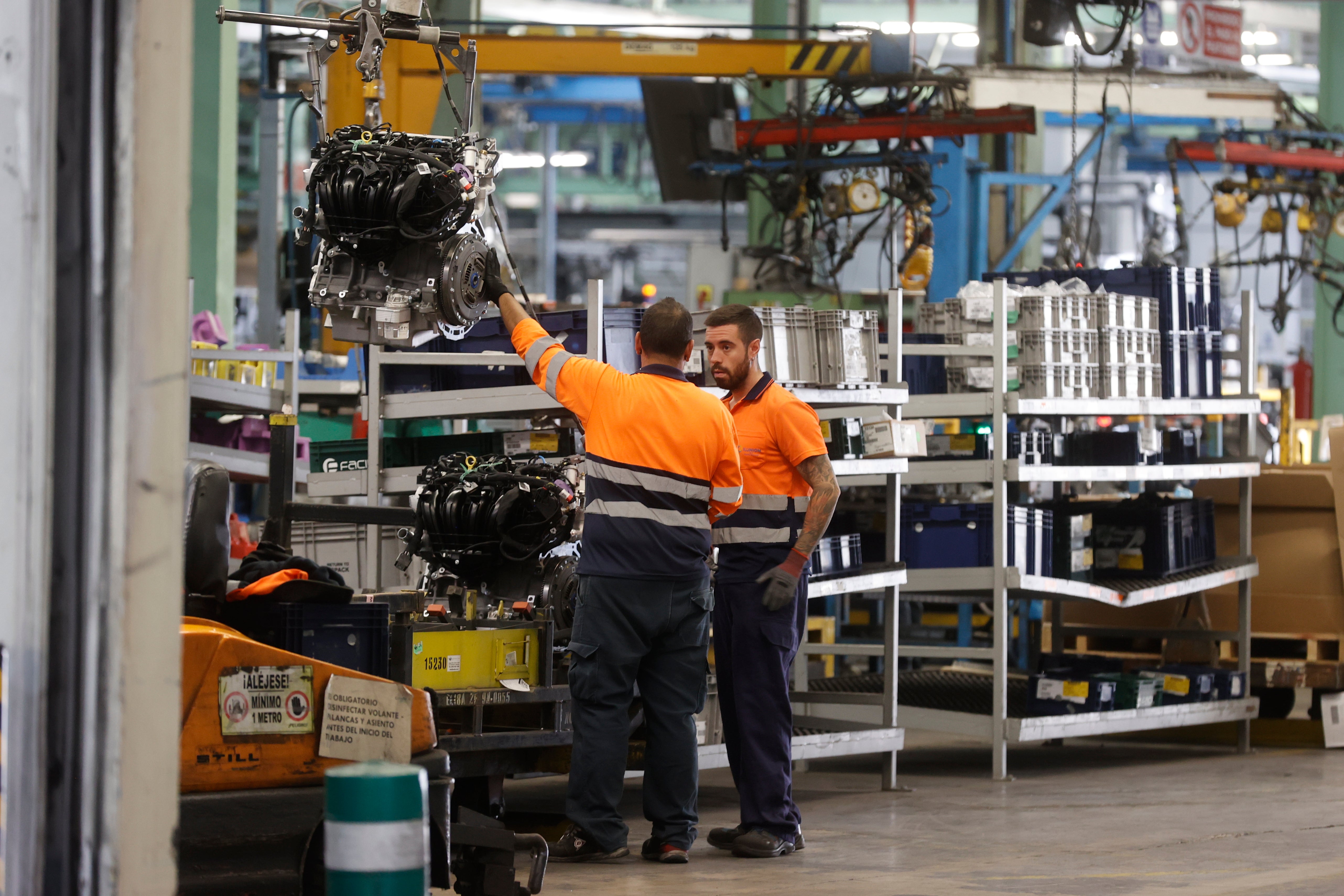 Dos trabajadores del sector industrial trabajan con maquinaria.