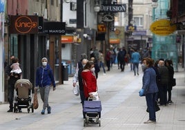 Vecinos caminan con mascarilla por el centro de Torrelavega durante la pandemia.