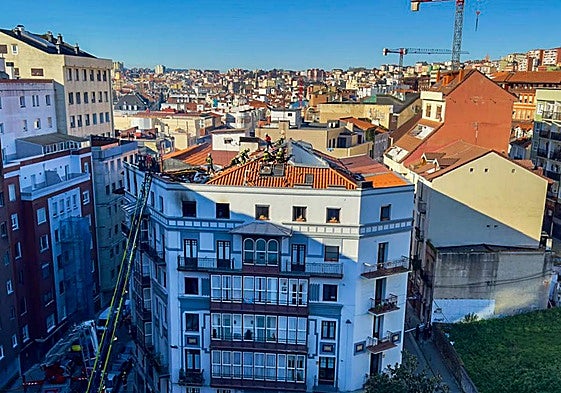 Los bomberos trabajan en la extinción del incendio desde el tejado del edificio de Juan de la Cosa