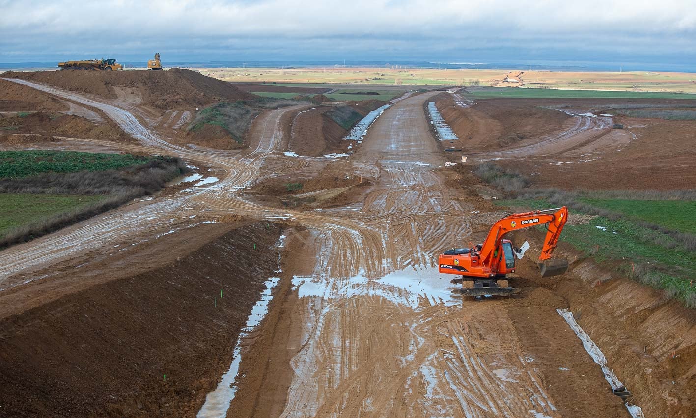 Una pala sortea las grandes acumulaciones de agua que se repiten estos días por muchas partes de las obras, un obstáculo añadido.