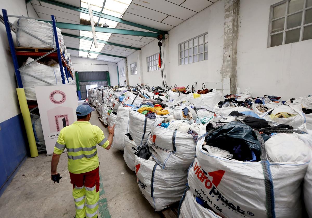 Un operario de Recogida de Residuos trabaja en el almacén del servicio, abarrotado de ropa.