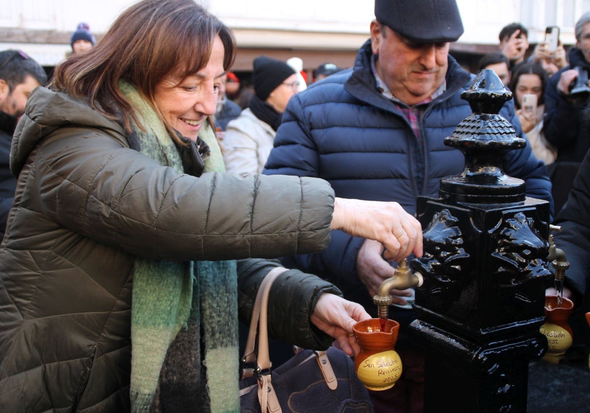 Una mujer abre uno de los dos caños de la fuente de la plaza de España para tomar vino.