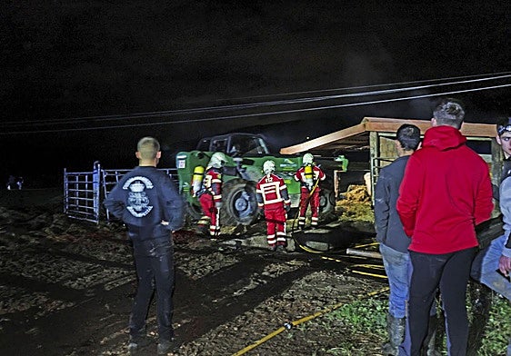 Los bomberos de Valdáliga, en el establo incendiado.