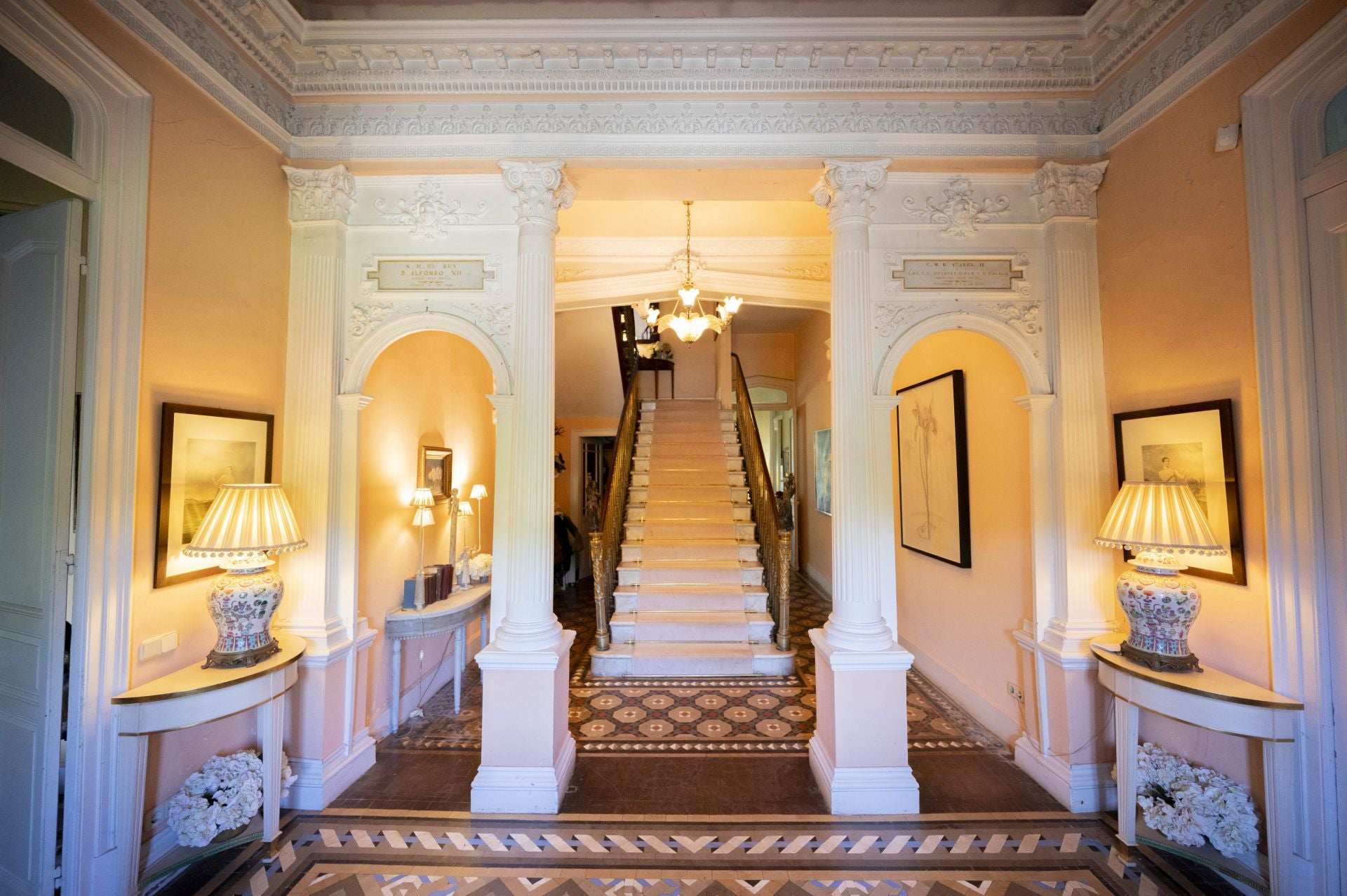 La entrada de la casa se compone de varios elementos decorativos y escaleras en colores cálidos.