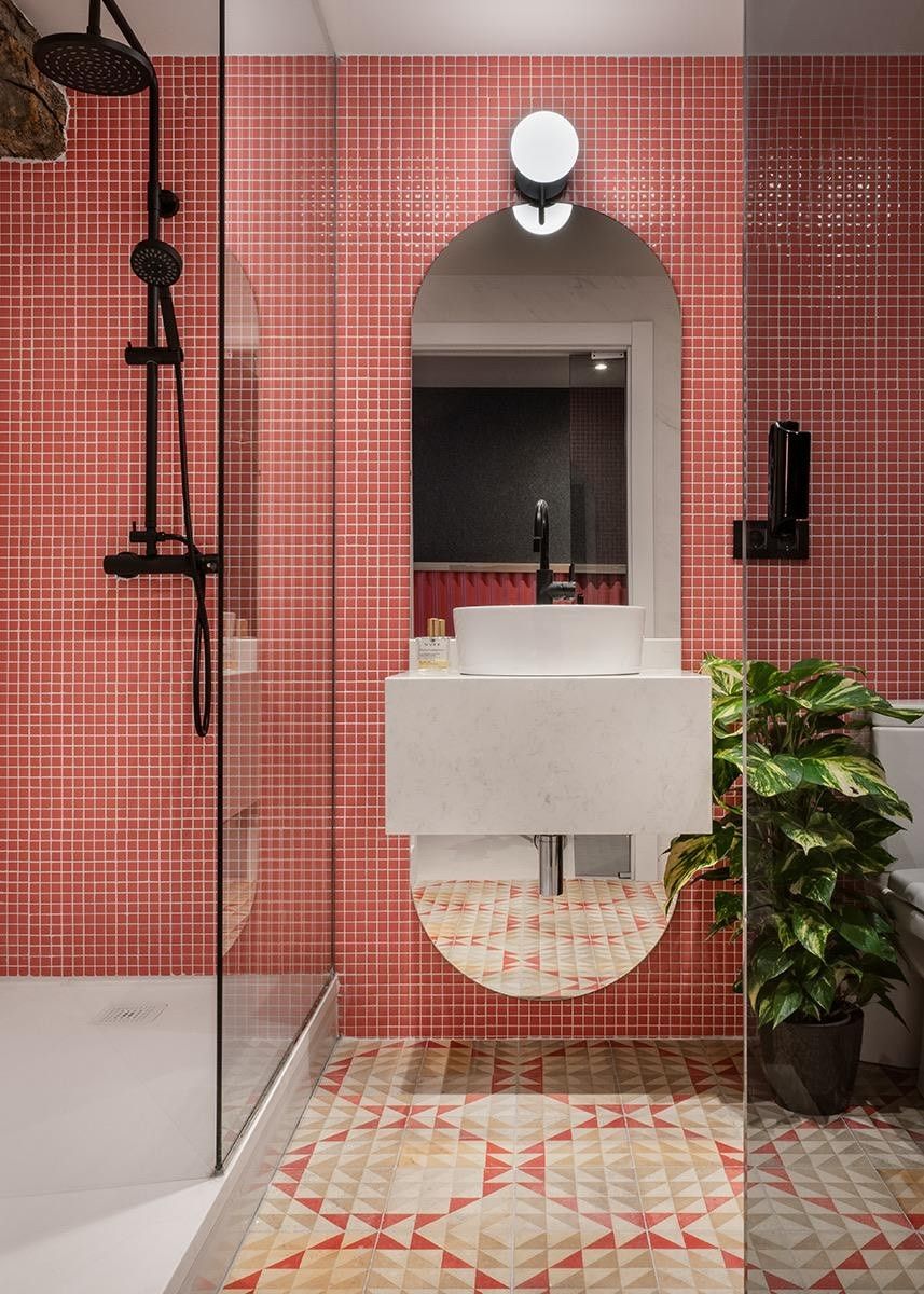 Perfecta combinación de azulejos de mosaico rojo en la pared y suelo geométrico que genera un ambiente vibrante con materiales de Lostal.