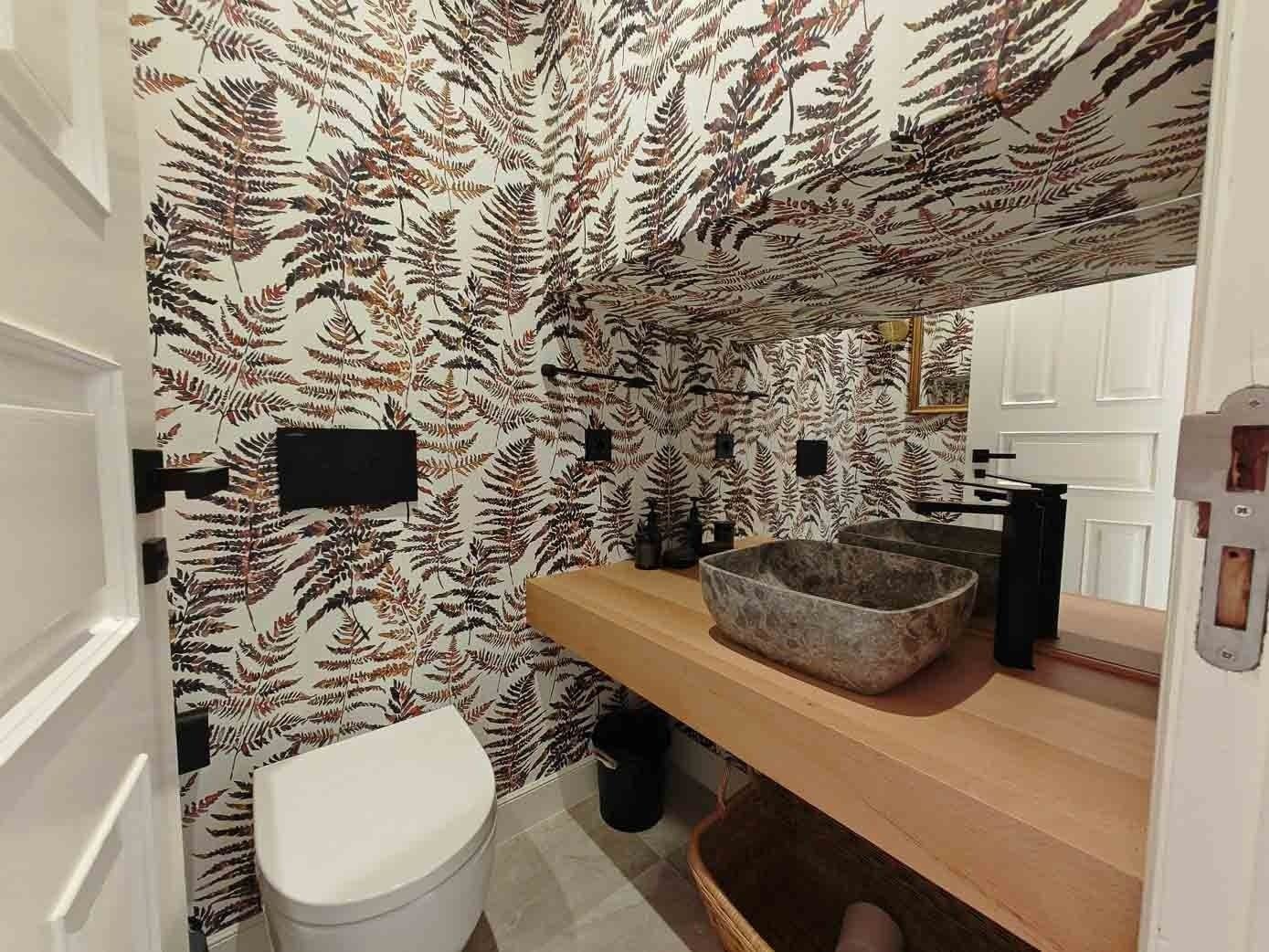 Elegir un papel pintado de motivos naturales ayuda a crear un aseo diferente. En este baño, ubicado en un piso de la capital cántabra, destaca también el lavabo de piedra natural que aporta textura y elegancia.