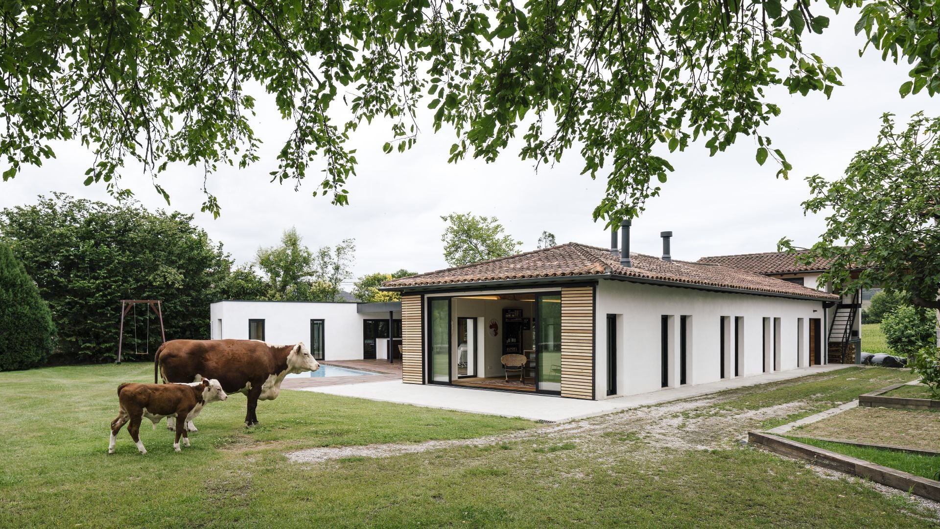 Fachada principal de la casa, con una vaca y un ternero de la ganadería de los Crespo en el jardín.