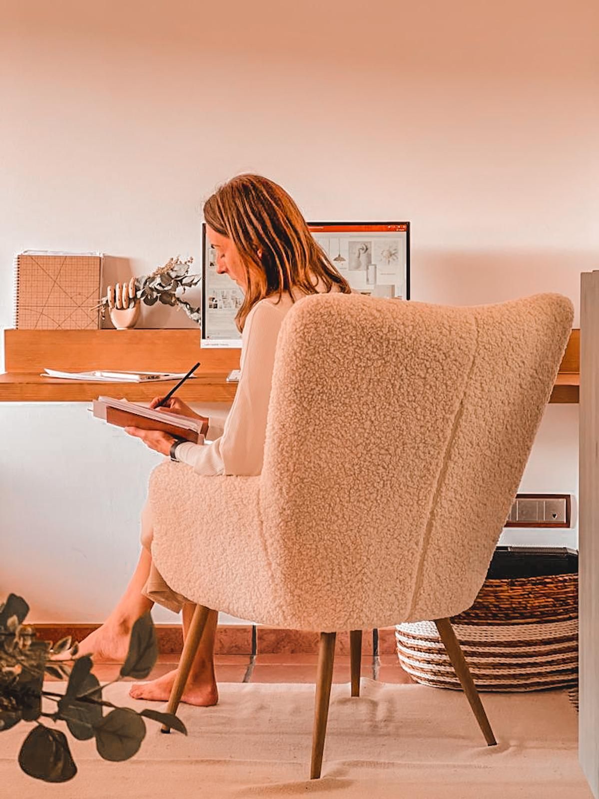 La 'home stager' Cristina Rumoroso (#lacasucadelcolumpio) en su lugar de trabajo de casa sentada en un sillón de tejido bouclé.