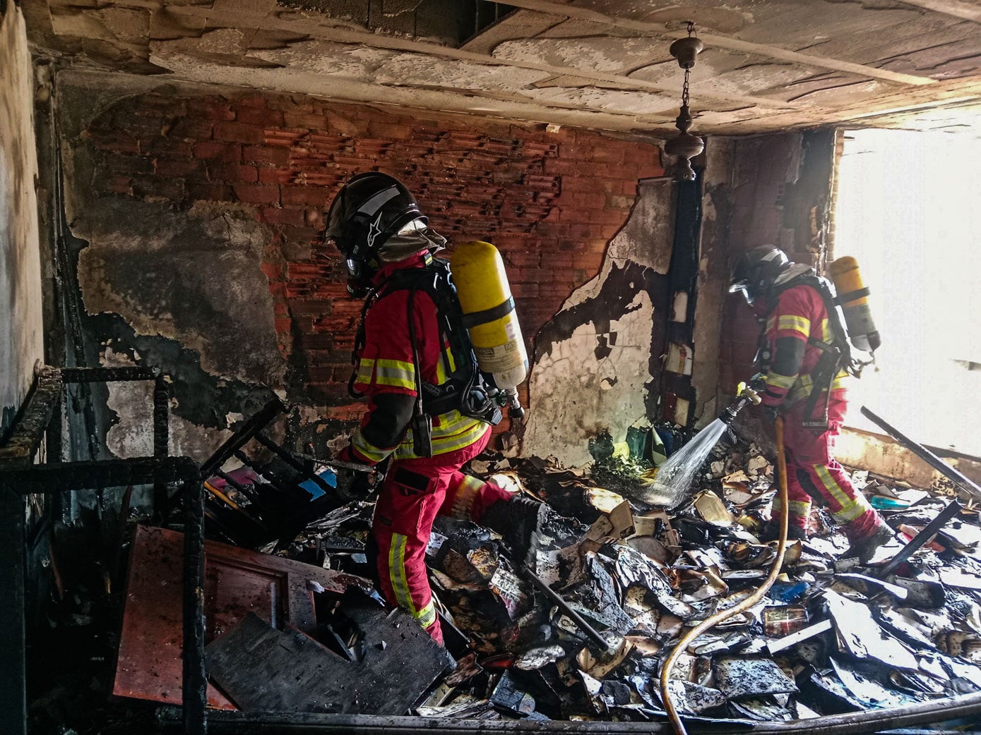 Bomberos trabajan en la extinción definitiva de las llamas, en el piso calcinado por el fuego, en la recta final de la intervención. 