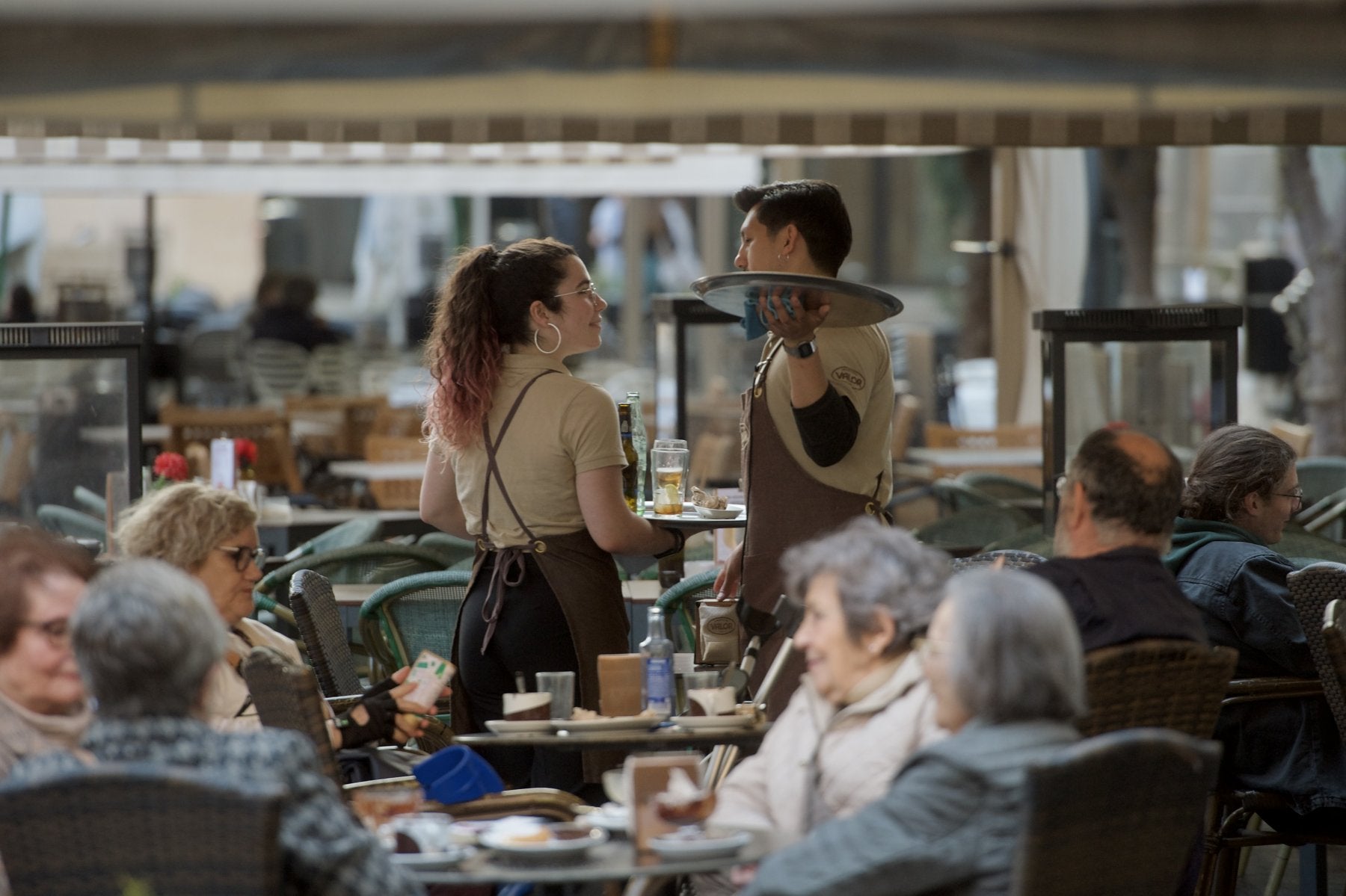 Dos camareros, que forman parte de uno de los sectores que se beneficiarán del cambio, atienden una terraza.