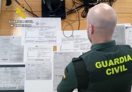 Un agente de la Guardia Civil examina los documentos falsificados.