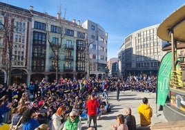 Alumnos atienden sentados en la Plaza Mayor, durante la entrega del cheque en el quiosco, a la Asociación Española Contra el Cáncer.