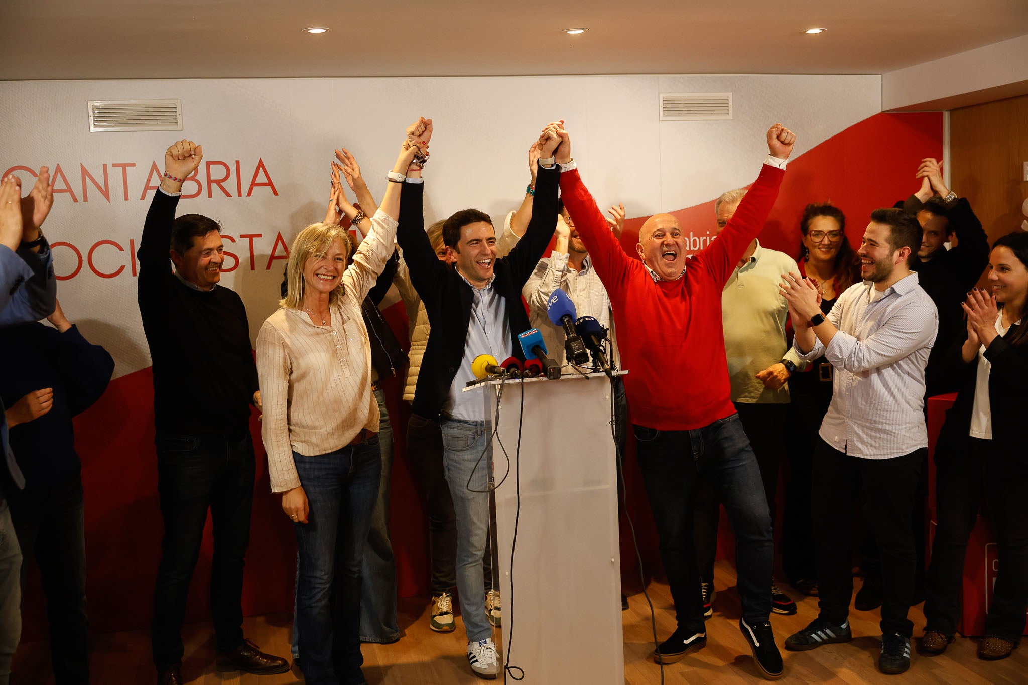 Casares alza los brazos en señal de victoria flanqueado por la alcaldesa de Castro, Susana Herrán, y el alcalde de Cartes, Agustín Molleda.